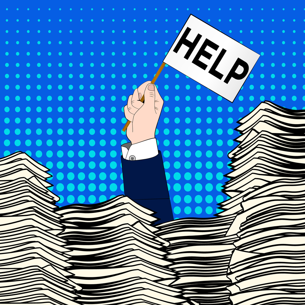 Hand of caucasian businessman emerging from office desk loaded of paperwork , invoices and a lot of papers and documents holding message card asking for help